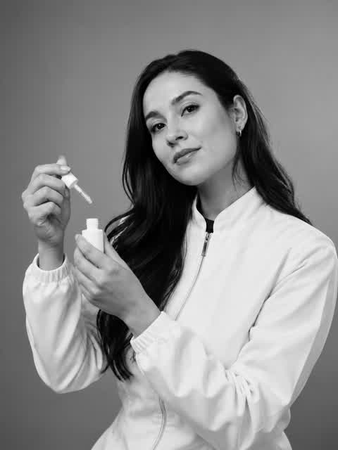 The founder of Harmony Beauty Lab with a dropper bottle, black and white